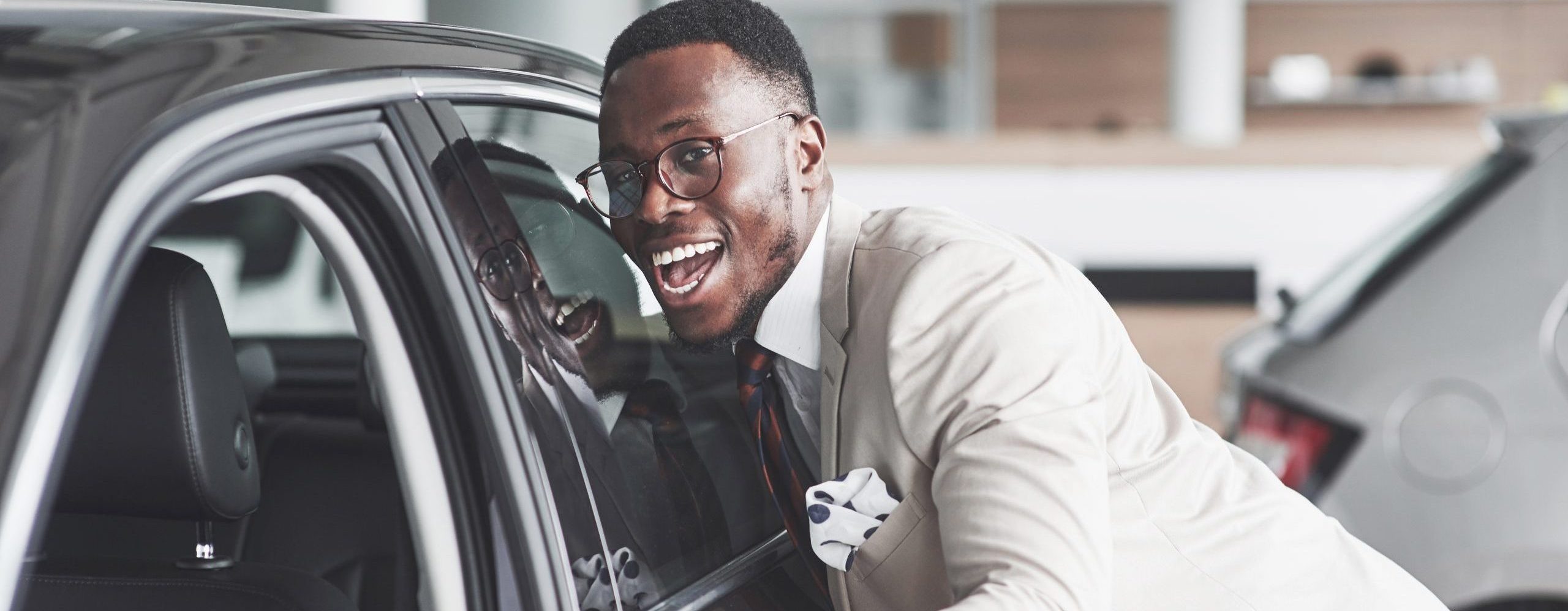 African man looking at a new car at the car dealership.